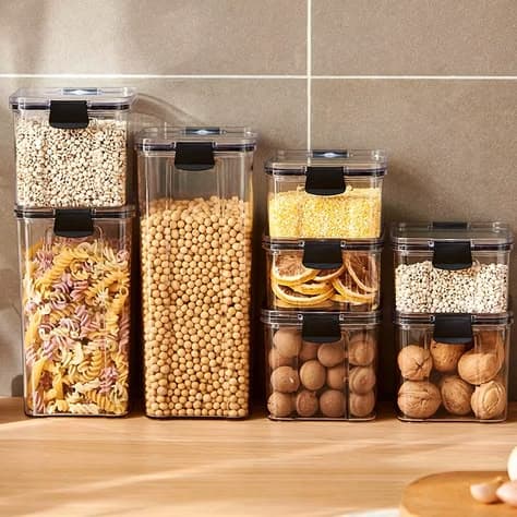 Clear stacked jars of pasta, chickpeas and nuts on a kitchen counter